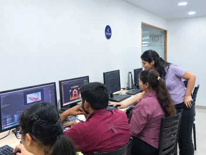 A trainer reviewing design work with students at their screens