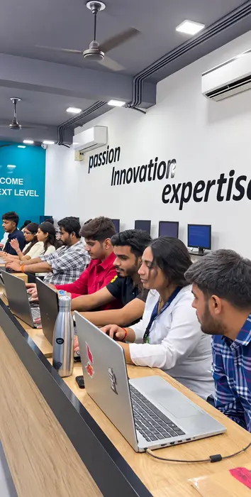 Students coding on laptops beneath the “passion, innovation, expertise” wall