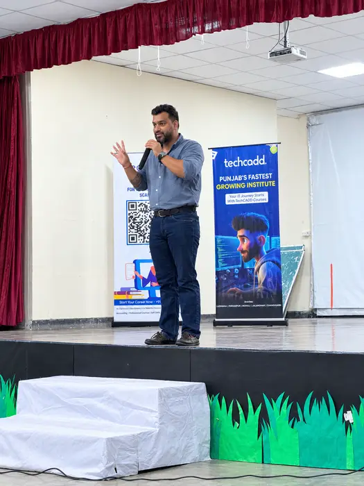 Speaking to students on stage, techcadd banners alongside