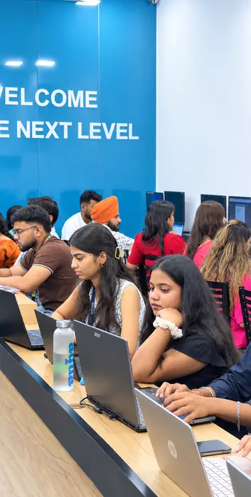 A full lab of students at work under the welcome wall